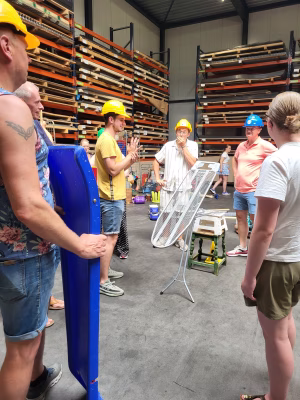 Medewerkers met bouwhelmen bouwen een kettingreactie in de hal van Almetaal